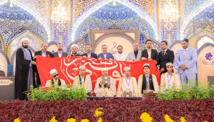 راية المولى أبيّ الفضل العباس تعانق راية أمير المؤمنين بعد حصول فريق النجف الأشرف على المركز الأول في المسابقة القرآنية الفرقية الوطنية الخامسة
